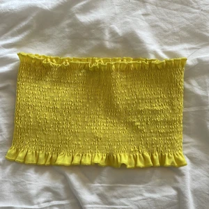 Gul bandeau från Gina tricot. Xs - Gul bandeau från Gina tricot med volanger. Storlek xs. Aldrig använd. Säljer för 15kr+ frakt.