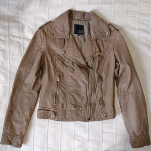 Gianini - Beige skinnjacka/läderjacka - storlek 36 - Beige/brun skinnjacka från Gianini. Äkta läder. Skitsnyggt modell med flera fickor med dragkedja. Använd bara någon enstaka gång - så gott som i nyskick. En del små bruna fläckar/märken i lädret, som funnits där hela tiden. Storlek 36.