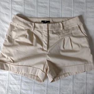 Beigea shorts/kostymshorts, storlek 34 - Beigea shorts. Sparsamt använda. 98% bomull och 2% elastan. Storlek 34.
