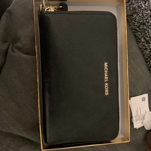 Äkta Michael Kors plånbok - Säljer min fina plånbok som jag haft i ett år men knappt använt, finns en låda till och är i fint skick som ni ser. Ni får gärna komma med bud också. Kostar över 1000kr i nypris.  Materialet är i skinn och fodret textil. Finns myntfack, dragkedja och plats för massor av kort och sedlar. 