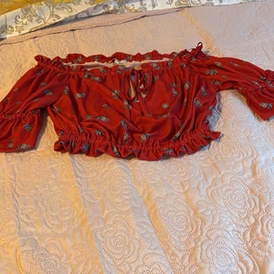 Sommrig off-shoulder topp - Stretchig offshoulder topp med ananas print. Ett hål mellan brösten med ett band. Kortärmad.