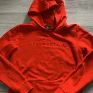 Röd Peak Performance hoodie stl 170. Inte använd. Ser ut som ny.