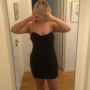 Svart klänning  - Svart klänning med guldkedjor. Från Elsa Hosk kollektion med BikBok för några år sedan! Säljer den för att den blivit för stor! Storlek L. 