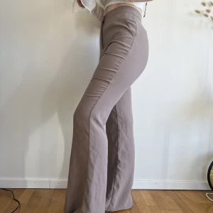 Brunbeiga kostymbyxor  - Brunbeiga kostymbyxor från Nelly, storlek 32 men passar mig som är 34-36. Fint skick, inget att anmärka på. 