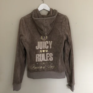 Juicy Couture zip up hoodie brun med text  - En brun tjocktröja från Juicy Couture. Tröjan är i använt skick, texten har spruckit och tyget på tröjan är en aning slitet. Storlek XL men är antagligen en barntröja och sitter som en S/M. Om varan inte betalas inom 24 av vinnare säljs tröjan till annan.