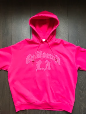 Oversized rosa hoodie - Oversized rosa hoodie med broderat tryck. Fleece-material på insidan och stor luva. Använd några gånger, bra skick :)