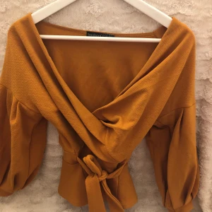 Omlott topp - Fin omlott tröja med bra material. Envärd fåtal gånger. Dom andra två bilderna är hur tröjan ser ut och hur den sitter på! Jag säljer den orangea inte grön!!!