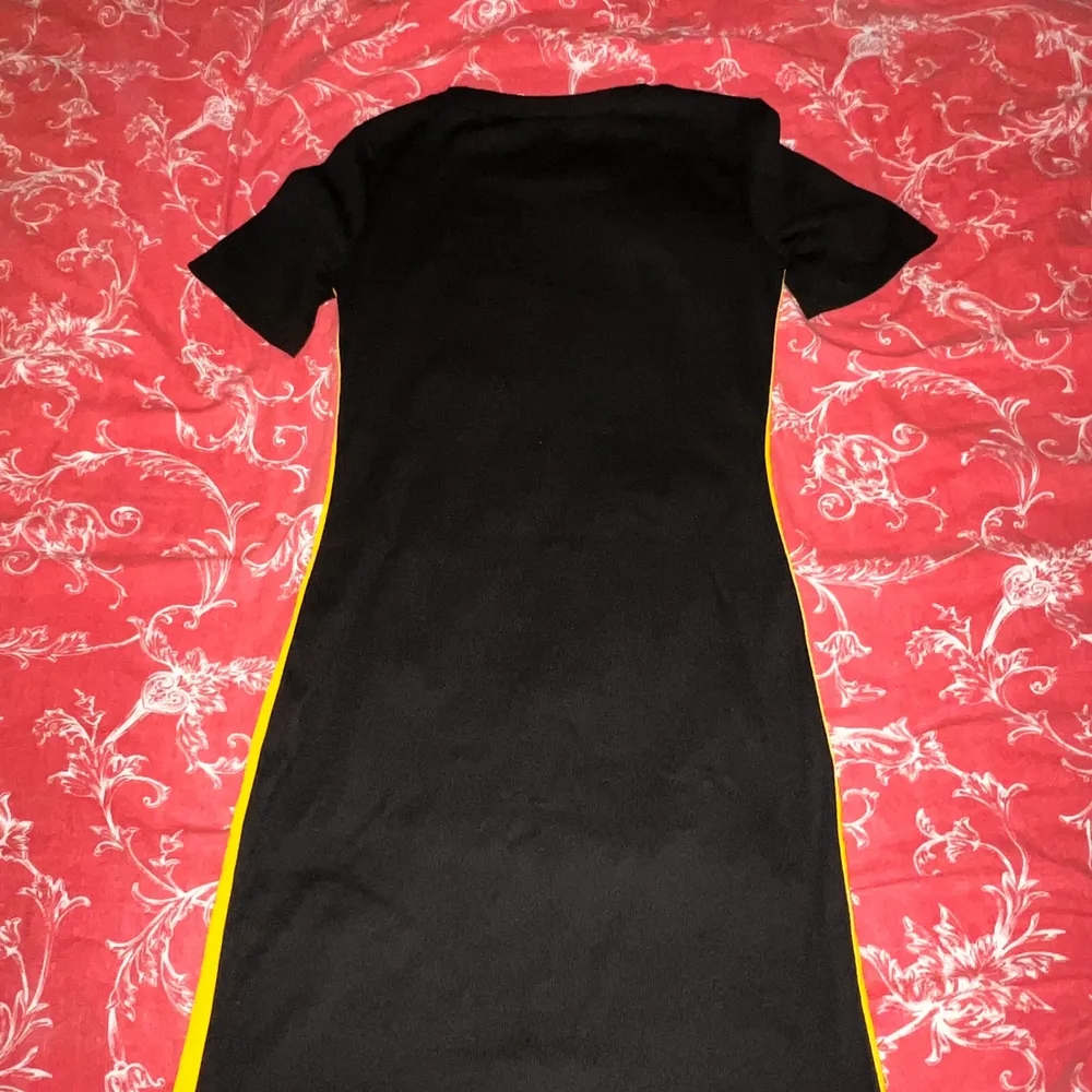 En klänning som är svart men med gul & vit rand. Klänningar.