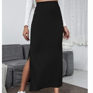 Högmidjad svart kjol med slits - Kjolen är lång, stretchig och har en slits vid låret. Köptes för 1 år sedan (100kr) men är i nyskick då den aldrig använts. Kjolen är i tunt material!