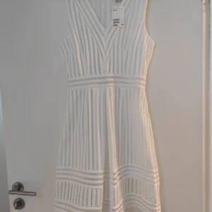 Klänning från HM  - Väldigt söt och tidlös. En kort ärmlös klänning i strukturvävd kvalite. Utställd kjol med motveck fram. Fodrad. Helt ny. 