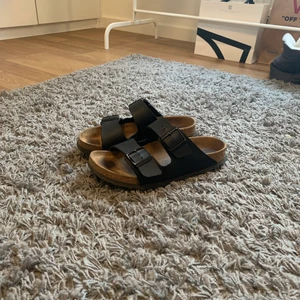 Birkenstock i storlek 38, passar 39-40 - Birkenstock nu till salu✅  Säljer mina Birkenstock nu på grund av att jag har växt ur dem, de är använda ca 3-4 månader så fortfarande bra skick. En välldigt lyxig toffla som har en kork sula i botten och läder spännen. Ny pris 899 kr, mitt pris 449 kr.