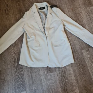 Kappa från Vero Moda i storlek S - Fin kappa från Vero Moda i storlek S. En annars fin och varm damkappa i färgen beige. Prislappkvar aldrig använd!