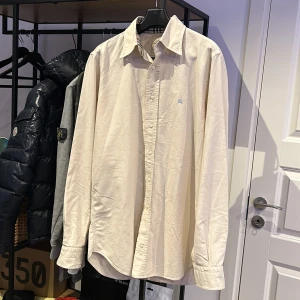 Burberry skjorta  - En vit/beige burberry skjorta i kanon skick, lite skrynklig på bilderna men en sväng me strykjärnet så är den som ny.  Nypris ca 3500kr, Skick 9/10 inga flaws, Storlek S.   Bara o skriva vid frågor eller funderingar!