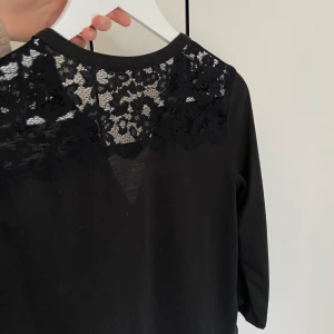 Svart tröja med spetsdetalj - Svart tröja från hm med spetsdetalj i ryggen och vringning framtill. 3/4 ärmlängd. Köptes för några år sedan och är sparsamt använd. Köpare står för frakten. ☺️