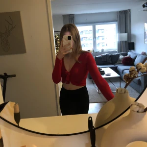 Knyt croptop från BOOHOO - Jättefin, röd croptop som knyts ihop på framsidan. Tunt o luftigt tyg, något lätt genomskinlig men inte jättemärkbart. Väldigt stretchigt tyg. Använd endast 3 gånger. Katt finns i hemmet!