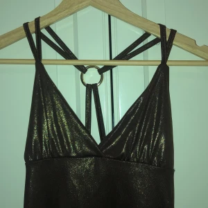 Brunt glittrigt linne - Brunt glittrigt secondhand linne med öppen rygg. Sitter tight mot kroppen. Passar xs-s