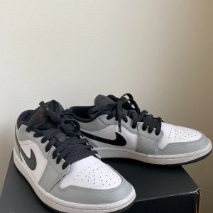 Jordan 1 low light smoke grey - Ett par fräscha Jordan 1 low i färgen light smoke grey. Retail priset ligger på ungefär 3600kr säljes för 2000. Lite creasing men annars väldigt fräscha. Box ingår. Storlek 40,5/7,5