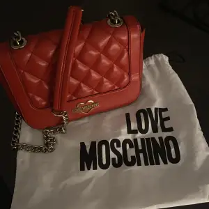 skitsnygg röd väska från moschino!! väskan är använd men ändå i fint skick! säljer den för den inte längre kommer till användning!!