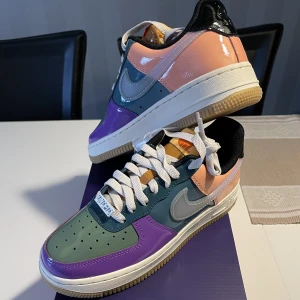 Air Force 1 Multi-Patent wild berry - Ett par sprillans nya sneakers från samarbetet mellan Nike och Undefeated! Skorna är gjorda utav patentläder vilket ger den här glansiga utseendet! Art nr på StockX: DV5255-500