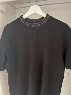 Acne Studios T-Shirt - Acne Studios T-Shirt i strl M & färg: Black/Grey Passform: Lite oversized  Köparen står för fraktkostnad!
