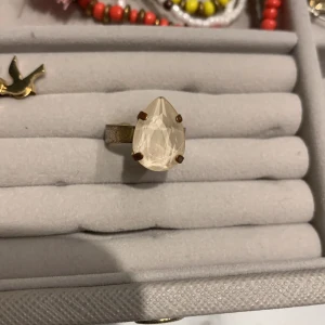 Caroline Svedbom ring - Ring från Caroline Svedbom med ljus rosa/beige droppformad sten. Fint skick . Justerbar och passar därför vem som helst