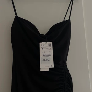 Klänning Zara - svart medellång med drapering  - En superfin och helt ny/oanvänd klänning från Zara med drapering och slits på sidan.  Storlek S 