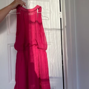 Fin rosa klänning från Drylake - En riktig pangklänning från Drylake! Det är en halterneck upptill och har sytts in lite i nacken för att sitta bättre.   Storlek S!