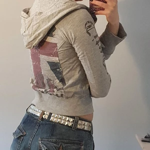 Zip up - Grå zipup tröja med tryck på armen och ryggen, dragkedja som går snett över och har spännen där uppe. Ganska liten då de är en barntröja egentligen i strl 146/152, skulle säga att den passar xxs/xs/s ungefär<3