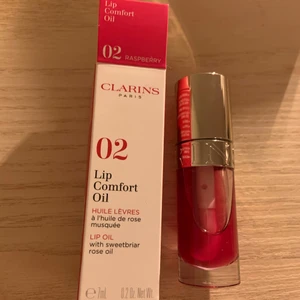 CLARINS Lip Comfort Oil 02 Raspberry - Helt ny och oanvänd läppolja från Clarins, har endast tagit ut ur förpackningen för att fota. Sista bilden är tagen från Kicks hemsida där man kan se hur färgen ska se ut på. Jag har fått den i gåva och säljer pga att jag redan har massor av läppglans i alla dess former och behöver helt enkelt inte ett till just nu 😊. Superfin läppolja med plumpingeffekt och diskret färg.