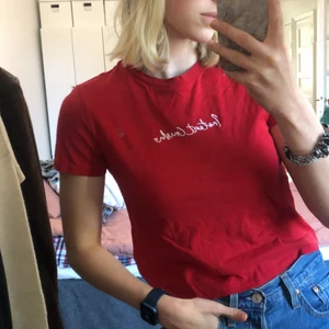 Röd T-shirt  - En röd och fin tshirt från HM med broderad text. Har endast användas ett fåtal gånger. Är i väldigt gott skick. 