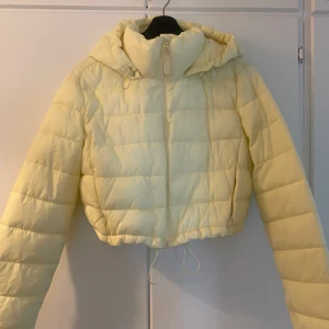 Cropped vårjacka från zara  - Helt ny vårjacka från ZARA, i färgen baby/ljus gul. Man kan spänna in den i magen beroende på hur man vill den ska sitta. Samt spänna in den i luvan. Helt oanvänd.