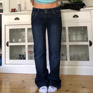 Lågmidjade jeans - Sjuuukt snygga lågmidjade jeans med fina detaljer dödskallar på backfickorna!! De är i superbra skick bortsett från stenarna som lossnat där bak (på dödskallarna)⭐️🤩 Midjemått: 80cm                                                               Innerbenslängd: 83cm