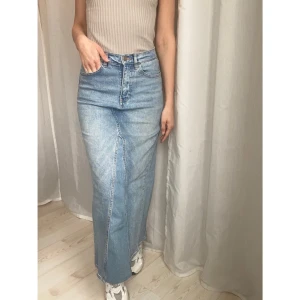 Jeanskjol - Kjolen är i denim. Lite stretchigt material.    Kjolen har hög midja och är omsydd av att par byxor.    Midja: 76cm Höft: 92cm Längd: 94cm