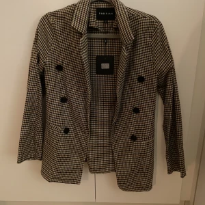 Rutig blazer från Parisian - Helt oanvänd med prislapp kvar, endast provad. Köpt från jfr.se, märket Parisian. Hund finns i hemmet och köpare står för frakt.