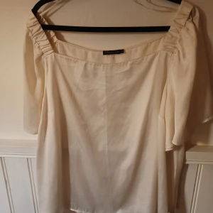 Satin blus  - Otroligr fin ljusbeige rak satinblus, kan användas off shoulders. 