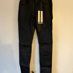 Svarta skinnbyxor  - Svarta skinnbyxor med detaljer på låren, oanvända Frakt tillkommer 