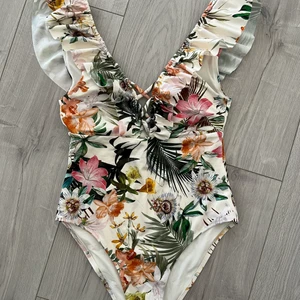 Oanvänd baddräkt - OANVÄND baddräkt med fin volang och detalj vid bröstet. Från H&M i strl XS/S (står båda storlekarna på lappen). Men skulle säga som XS mer. Nypris 399kr Mitt pris: 30kr  Skicka meddelande om du vill ha flera bilder. Vid snabb affär kan priset diskuteras. Kan mötas i Tyresö eller skickar! 