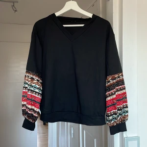 Tröja  - Svart tröja med mönster på nedre delen av armen. Använd 2 gånger