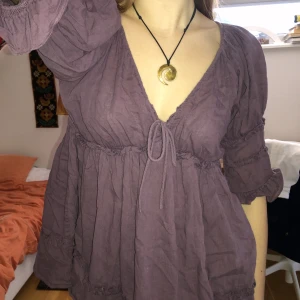 Lila blus - Blus eller tunika som är köpt på secondhand men har inte kommit till användning. Går att justera ringning med snöret. bra skick! Meddela för fler bilder eller liknande.