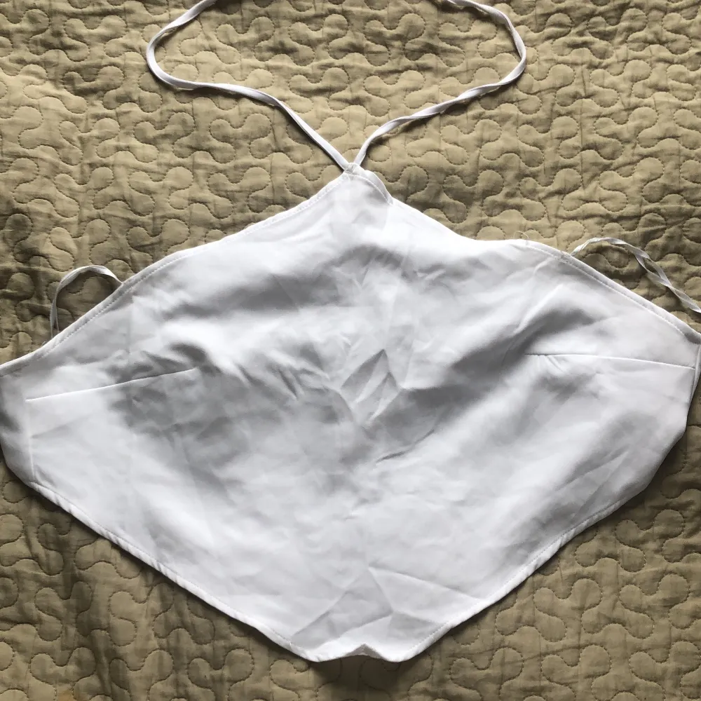 Ett vitt triangelformat linne med öppen rygg. Toppar.