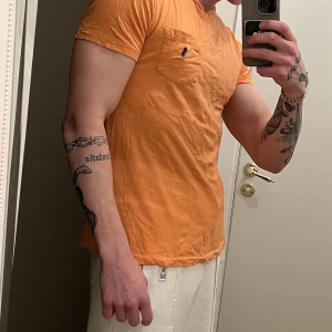 Polo Ralph Lauren T-shirt - Orange polo Ralph lauren T-shirt. Knappt använd och i gott skick. Nypris ca: 600-700:- OBS: kläderna är skrynkliga då de legat nerpackade.