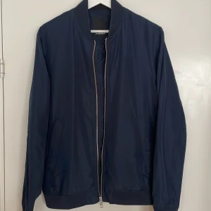 J.Lindeberg tunn jacka - Tunn jacka, J.Lindeberg, midjekort. Delvis vattenavvisande material samt fickor med dragkedja. Mycket sparsamt använd, storlek M.