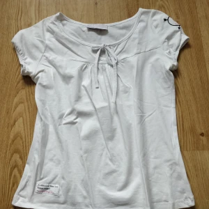 Vit topp - Söt vit topp med knytning och rester där fram. Är ganska tajt i armarna då det är barn storlek men passar bra på mig som brukar ha S! ❤️ Fint skick