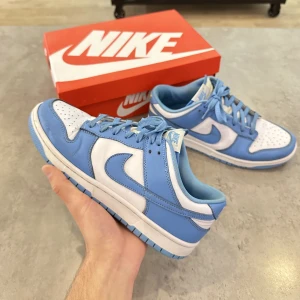 Nike Dunk Low UNC - Nike Dunk Low Retro UNC White / University Blue-White Blåa / Vita Använda, Ok skick enligt bilder ca 7/10 Size US 9 / EU 42,5  