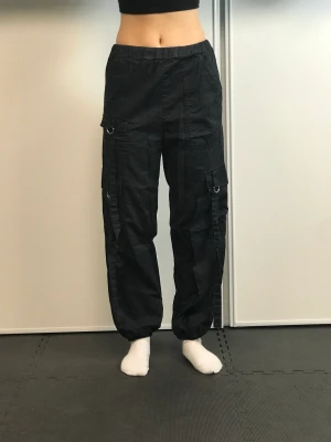 Cargo byxor  - Svarta cargo byxor med straps. Storlek 36 men liten i storleken 