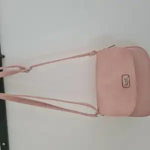 En söt liten rosa handväska med många fack. Blommigt foder.  Fint skick. 