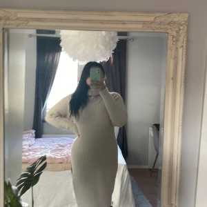 Stickad långklänning - Strl XS. Beige stickad klänning med slits på ena sidan. Med krage