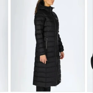 Swedemount jacka strl 34 - Härligt mjuk och bekväm jacka. Vind- och vattenavvisande material. Fast huva med justerbar dragsko. Hellång dragkedja med ett hakskydd. Två fickor med dragkedja. Logotryck. Vadlång modell.