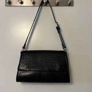 Svart handväska i skinninmitation  - Säljer denna superfina och praktiska handväska/axelväska. Smidig men rymmer väldigt mycket. Finns dragkedja vilket håller dina sker i gott förvar!  Pris går att diskutera🫶🏼