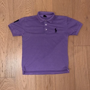 Lila Ralph Lauren piké  - Pikétröja från Ralph Lauren. Den är helt oanvänd och i super bra skick. Är medium men skulle rekomendera smal. 
